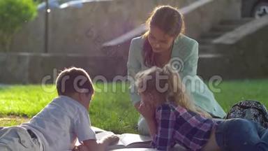 孩子的成长，年轻的女人在阳光下为坐在绿色草坪上的孩子阅读有趣的书